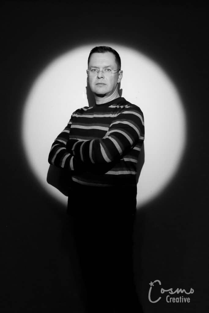 Man in striped sweater posing confidently in dramatic spotlight, showcasing bold portrait style from Cosmo Photo Booths' Spotlight Experience.