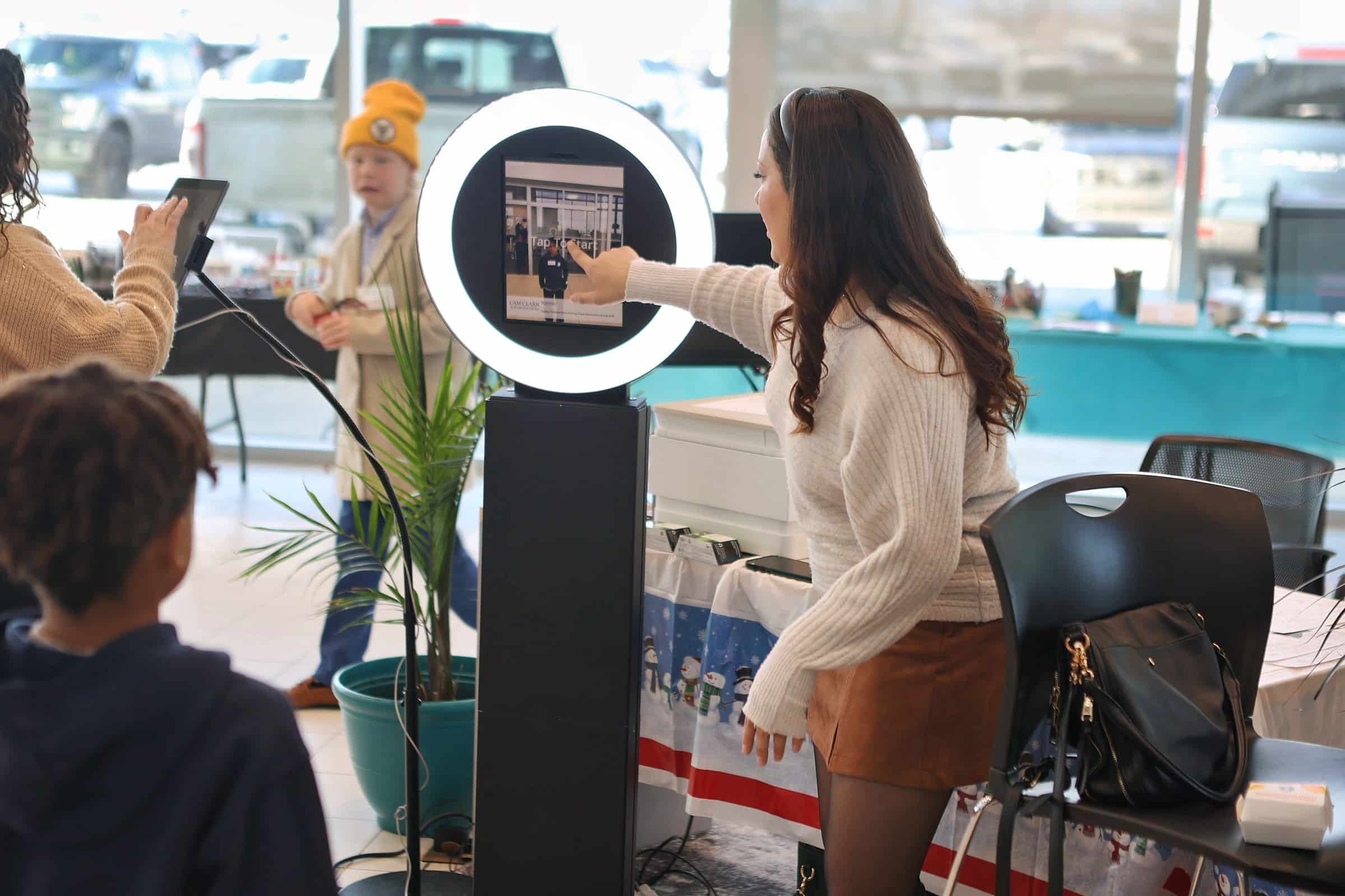 Digital photo booth with ring light and touchscreen interface, guest interacting with the booth at
