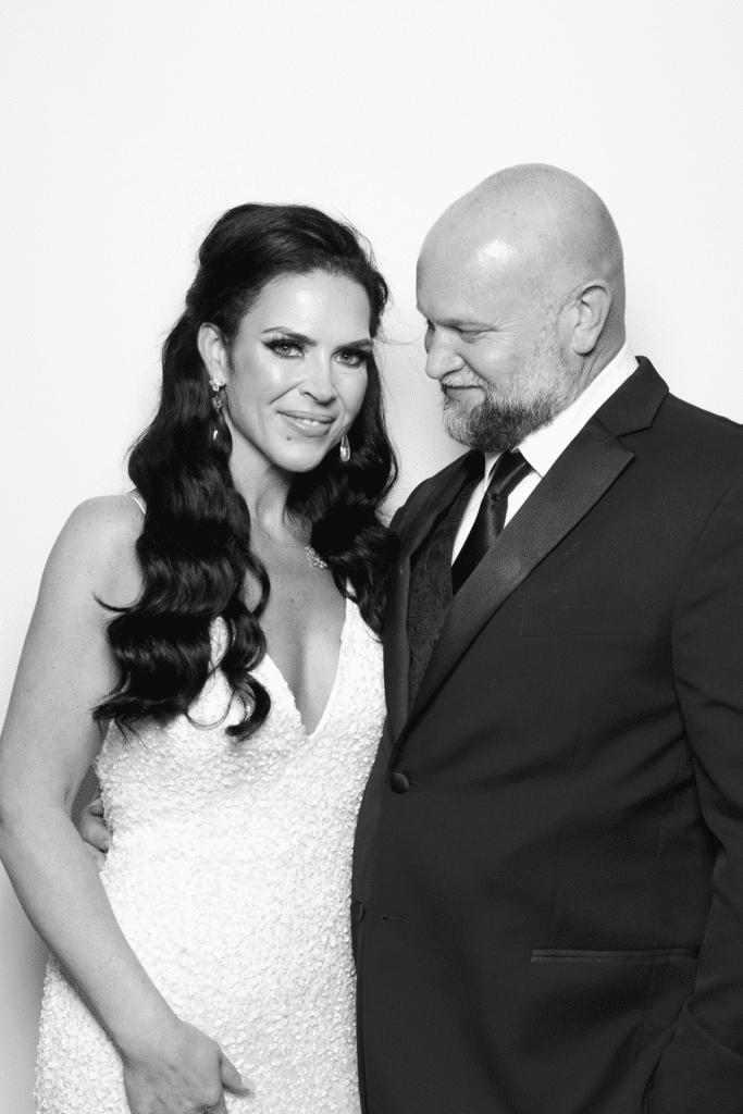 Couple posing in elegant attire, showcasing polished, studio-quality portrait style typical of high-end events, with a modern, clean backdrop.