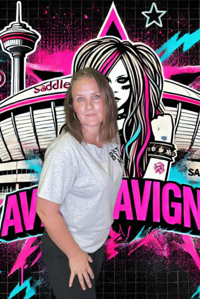 Woman posing in front of a vibrant, pink and black digital backdrop featuring a stylized graphic of a female figure and the text "AVRIL LAVIGNE," showcasing a modern photo booth experience.