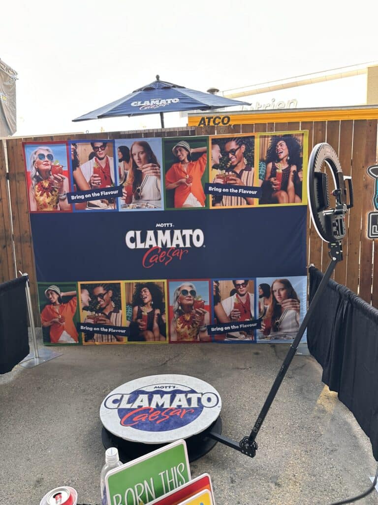 Western-themed photo booth setup featuring Mott's Clamato Caesar branding, vibrant backdrop with guests enjoying drinks, and a photo capture station for engaging Stampede celebrations.