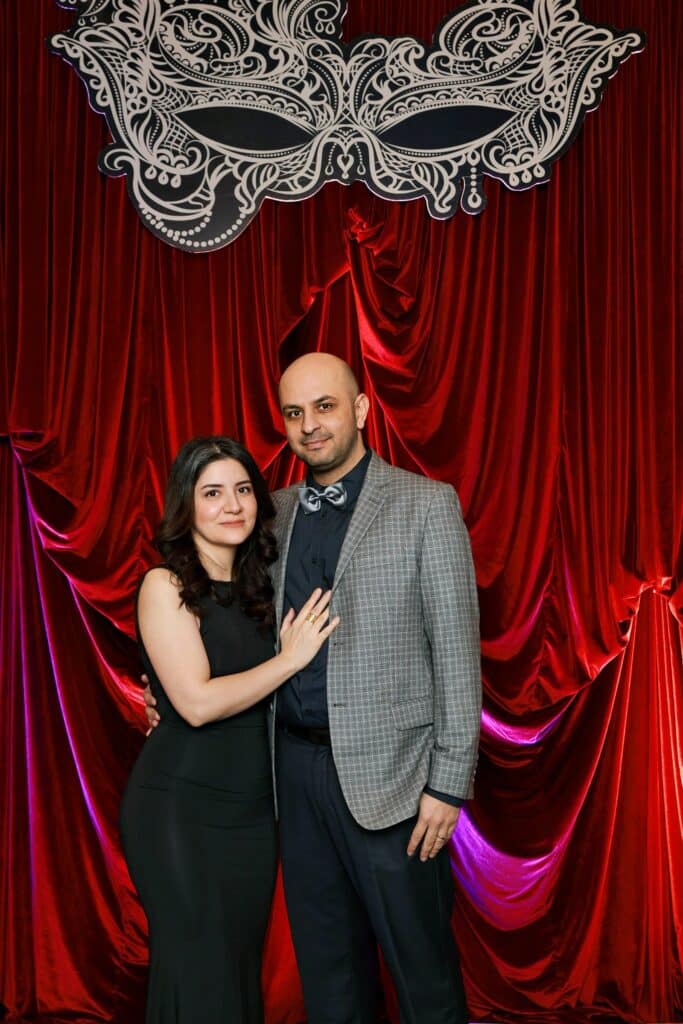 A coupe posing for a photo in front of a red velvet backdrop