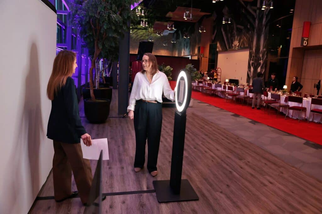 Two women at an event taking an image with a photo booth