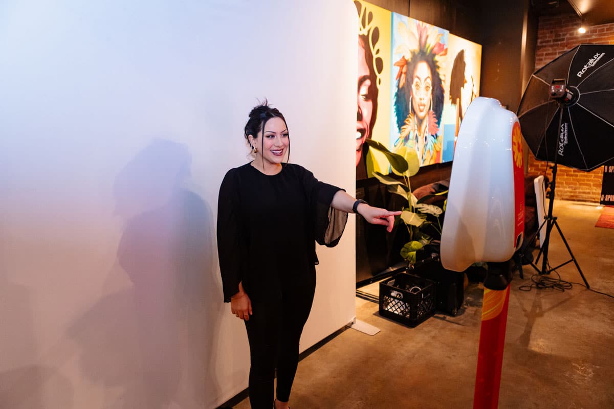 Woman interacting with a photo booth setup in an event space, surrounded by vibrant artwork, showcasing a personalized trading card experience for athletes at the U SPORTS Men’s Final 8 All-Canadian Gala.
