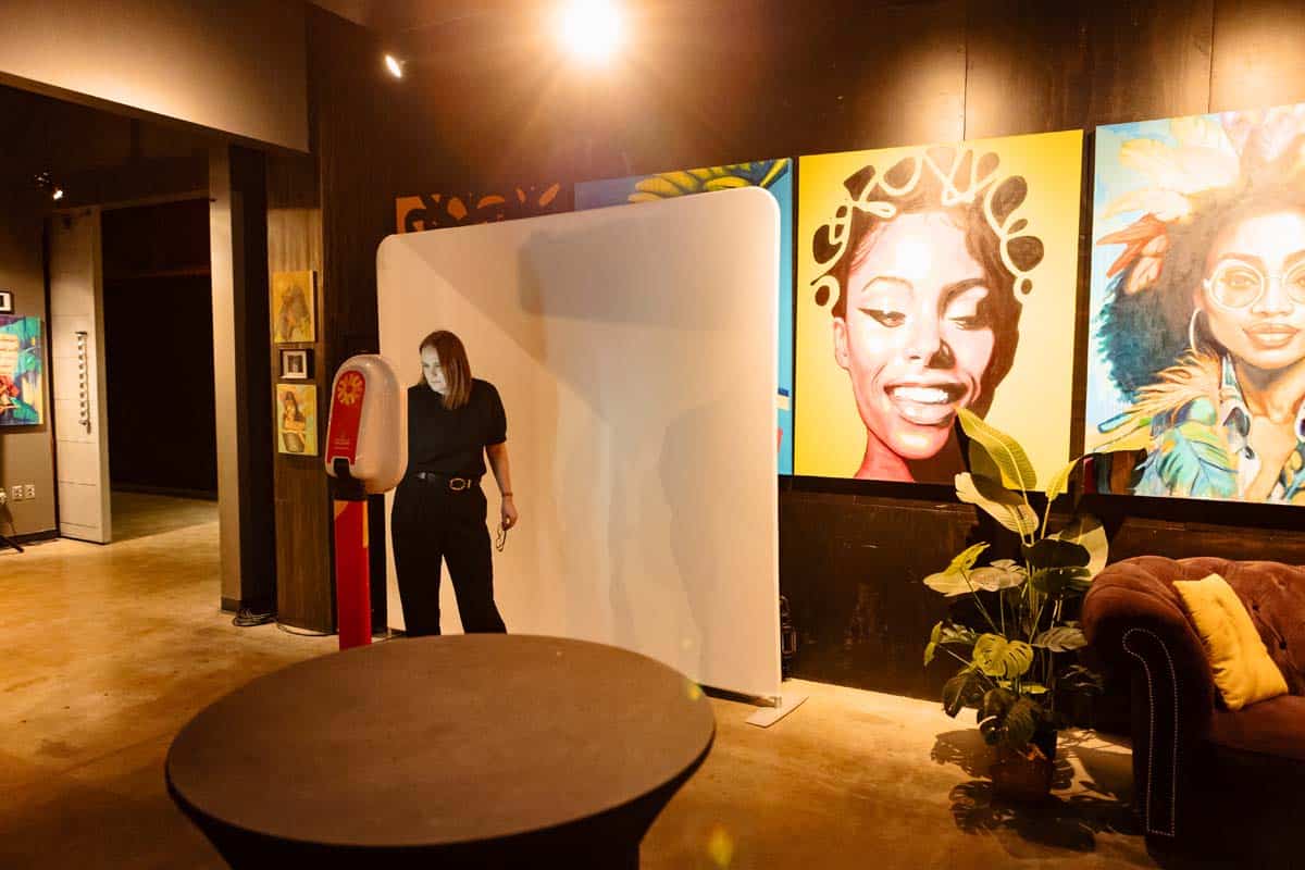 Interactive photo booth setup in Calgary venue, featuring a woman preparing to capture moments, surrounded by vibrant artwork and a plant, enhancing conference engagement and networking experiences.