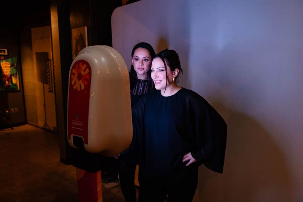 Two women posing in front of a photo booth at a Calgary conference, showcasing interactive engagement and memorable moments.