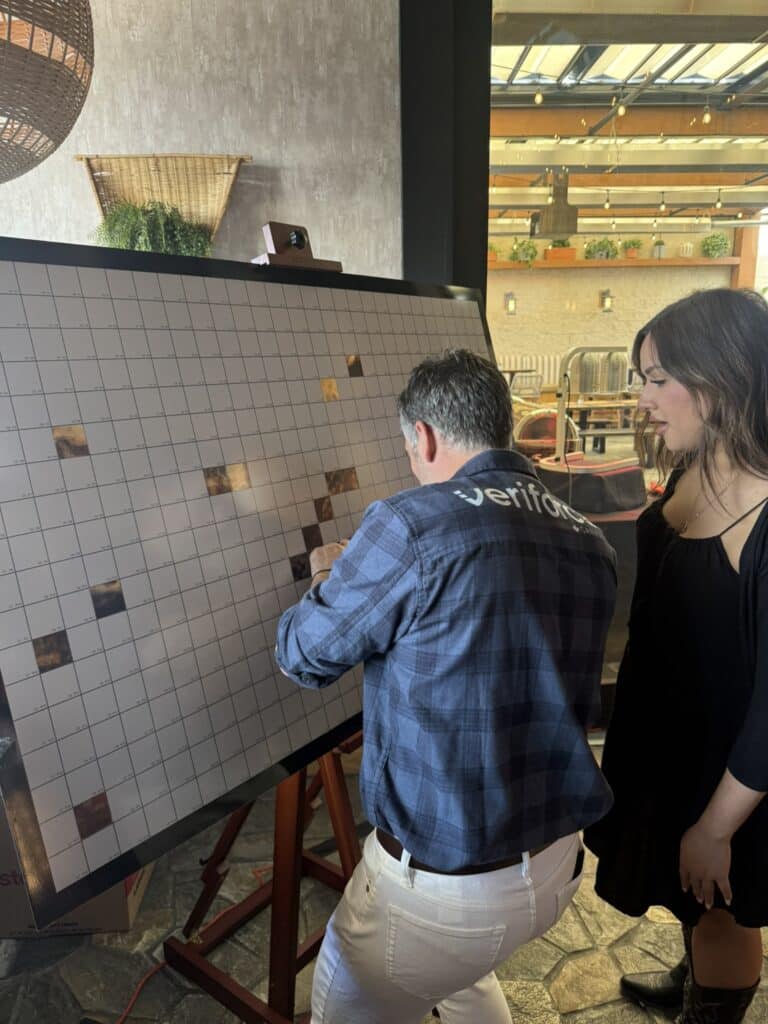 Veriforce guests placing mosaic tiles on collaborative artwork at Stampede celebration.