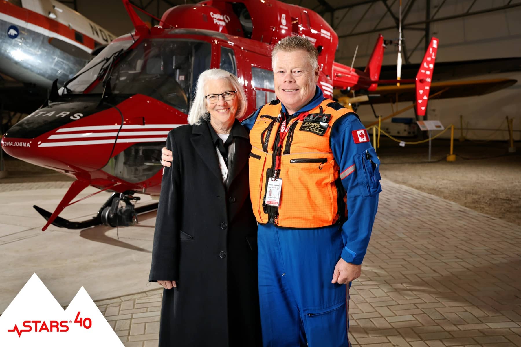 Guests posing for a portrait with a STARS helicopter, creating meaningful keepsakes at the 40th