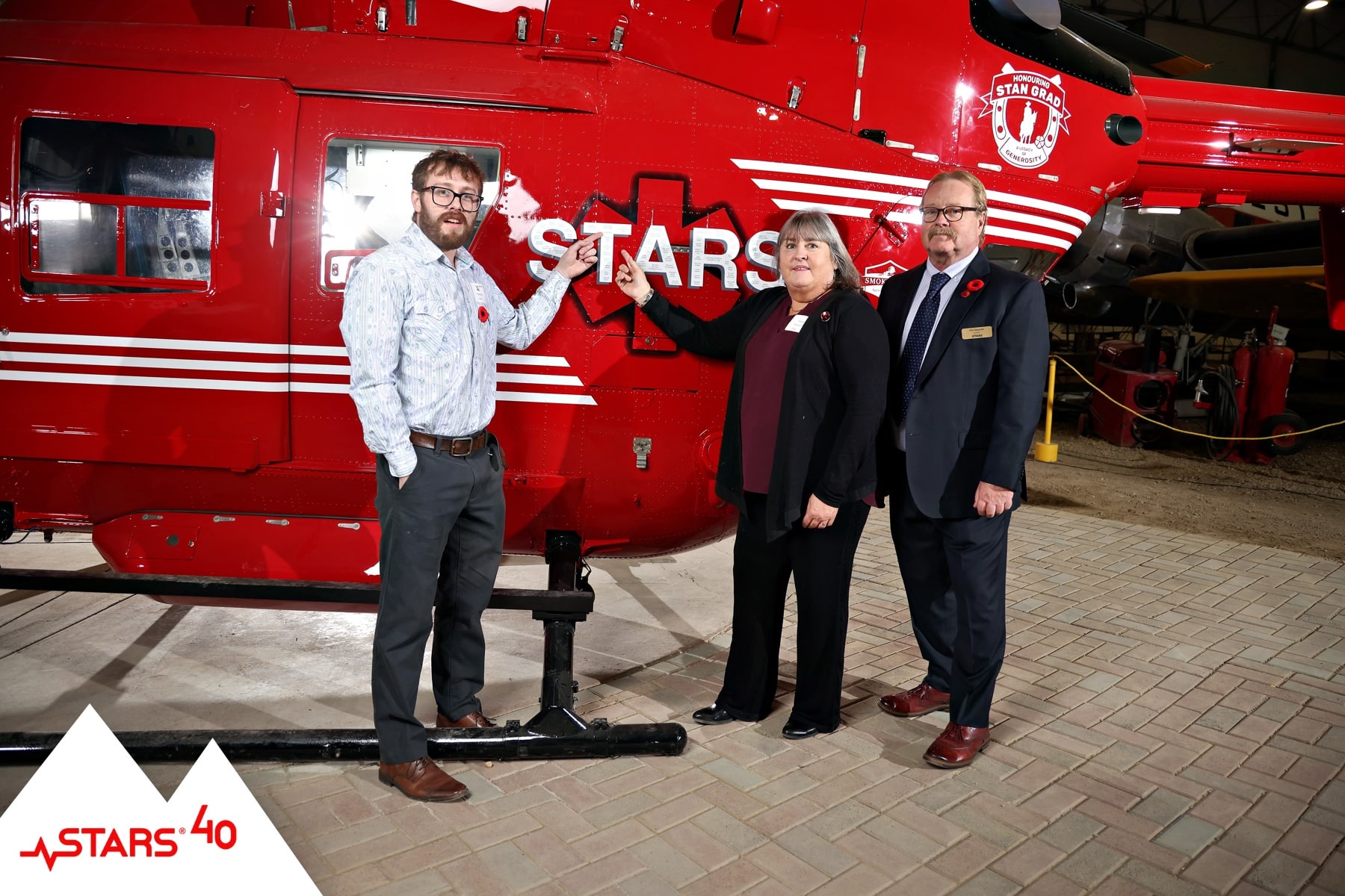 Guests posing for portraits with STARS helicopter, donor recognition branding visible.