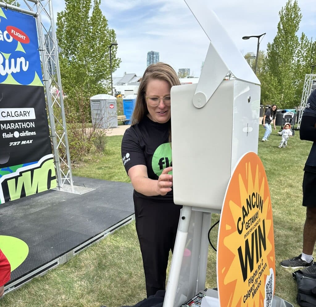 Flair Airlines branded photo booth at Calgary Marathon finish line festival, runners celebrating and capturing