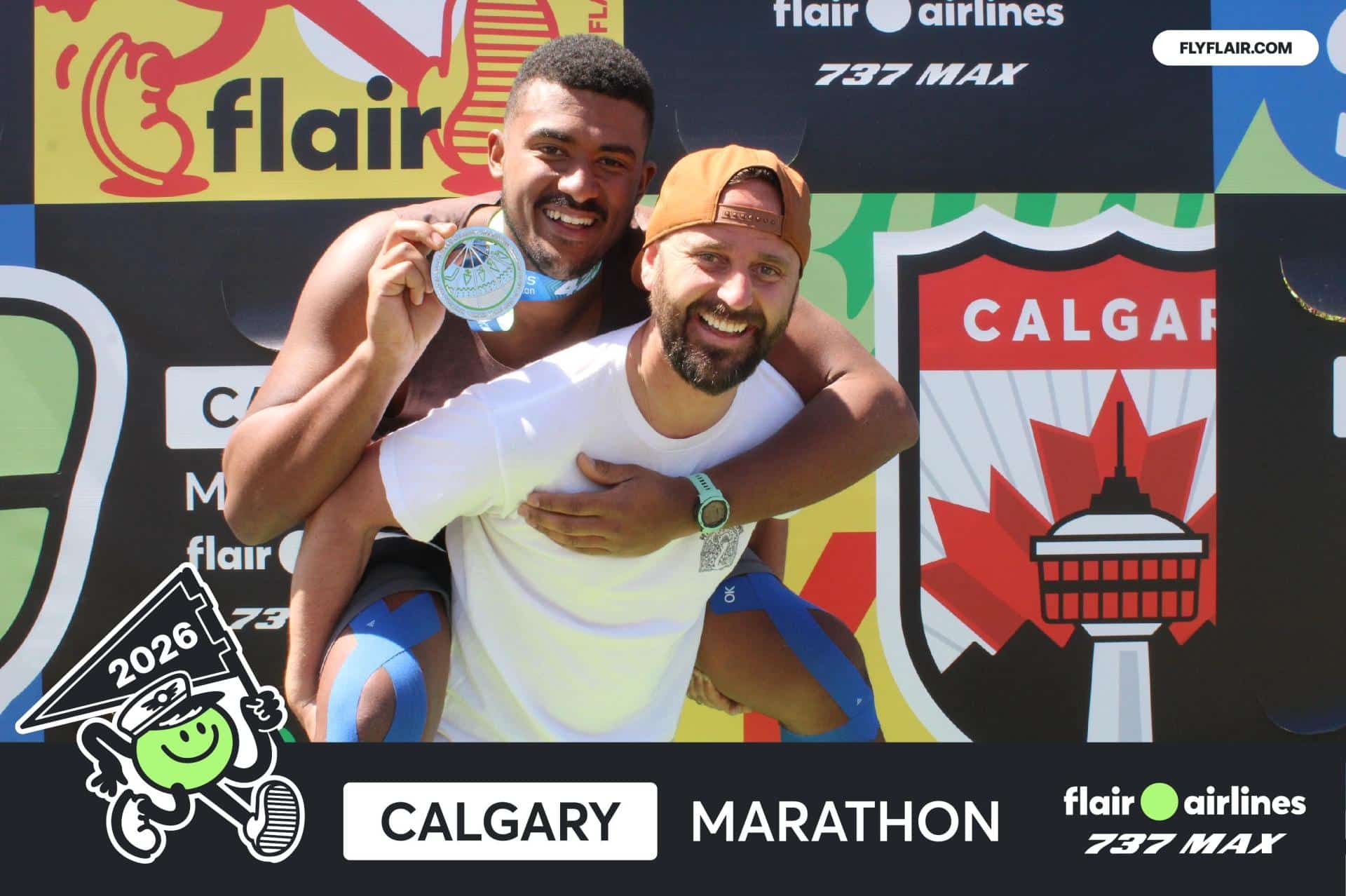 Man and friend celebrating Calgary Marathon victory with medals and branded backdrop.